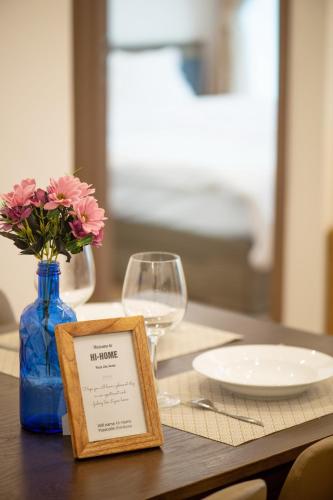 a table with a blue vase with flowers and a sign at Hi-Home Suites - Vinhomes Metropolis in Hanoi