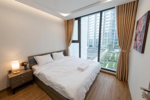 a bedroom with a bed and a large window at Hi-Home Suites - Vinhomes Metropolis in Hanoi