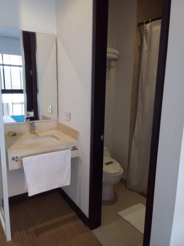 a bathroom with a sink and a toilet and a mirror at Suite Sumapaz Hotel in Melgar