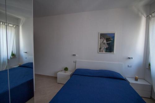 een slaapkamer met een blauw bed en een spiegel bij Affittacamere Caletta del Conero in Numana