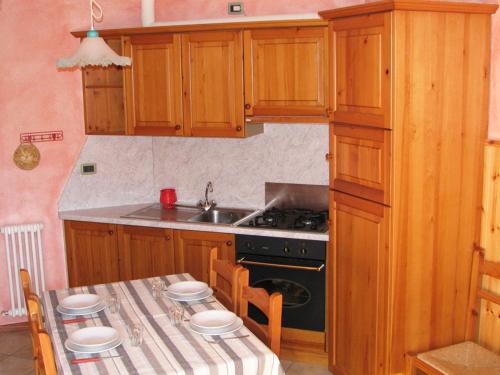 uma cozinha com um fogão e uma mesa com cadeiras em Residence Fior di Roccia em Campodolcino