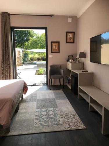 a bedroom with a bed and a tv and a sliding glass door at Un Moment à la Campagne in Pleuven