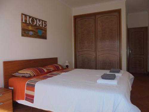 a bedroom with a large white bed with a wooden door at CasaDuarte "doMar" in Lagos