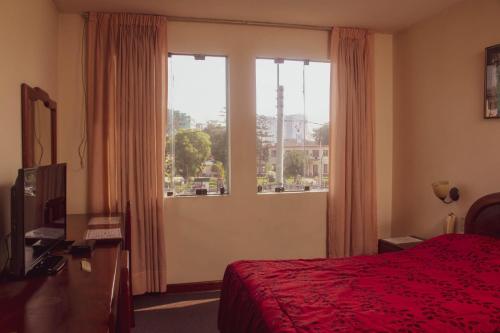 a bedroom with a red bed and a large window at Hotel Internacional in Lima