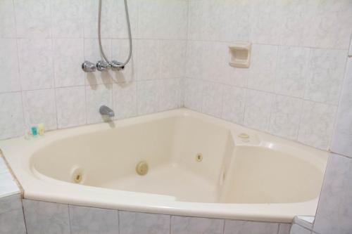 y baño de azulejos blancos con bañera blanca. en Hotel Internacional, en Lima