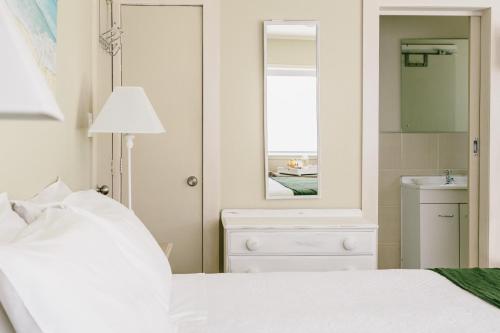 - une chambre avec un lit, un miroir et un lavabo dans l'établissement Studio on Petley, à Tairua