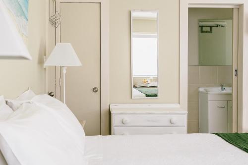 a bedroom with a bed and a mirror and a sink at Studio on Petley in Tairua