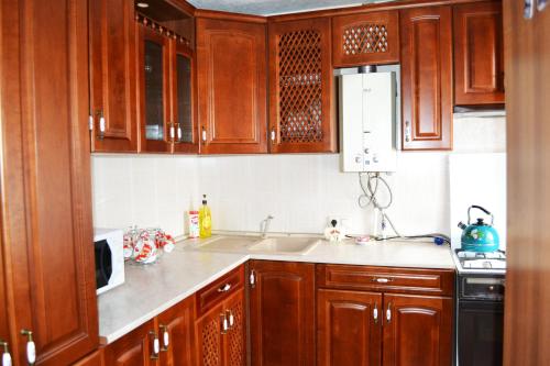 a kitchen with wooden cabinets and a sink at Apartamenty na Prospekte Pobeda Revolutsii 99 in Shakhty