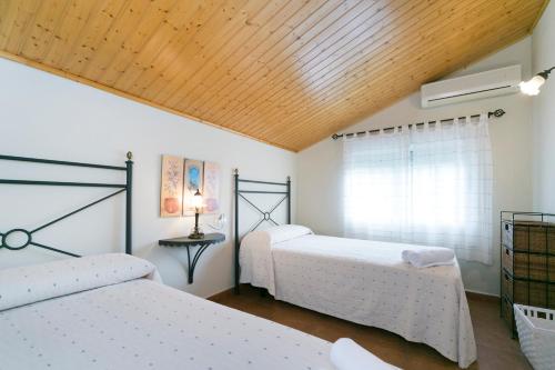 a bedroom with two beds and a wooden ceiling at Casa Rural La Cambreta in Crevillente