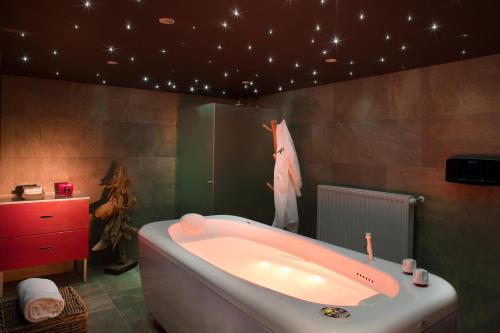 a bathroom with a bath tub and a tv on the wall at Hôtel & Spa L'Alta Peyra in Saint-Véran