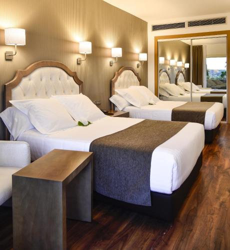 a hotel room with two beds and a mirror at Beatriz Toledo Auditorium & Spa in Toledo