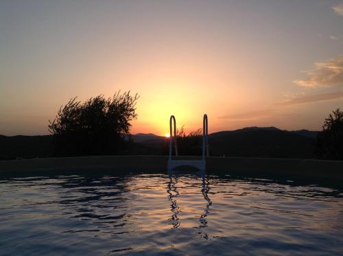 a sunset over a swimming pool with the sun setting at Agriturismo Prato Barone in Rufina