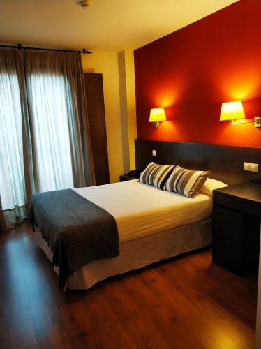 a bedroom with a large bed with a red wall at Hotel Puerta del Arco in Tudela de Duero