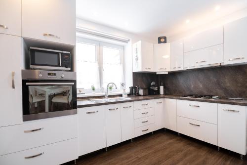 cocina blanca con armarios blancos y microondas en Apartment Gudi, en Tatranská Lomnica