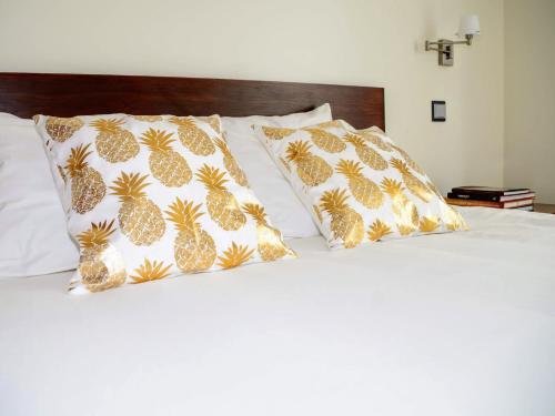 a bed with two pineapple pillows on it at Cabo da Vila Guesthouse in Ribeira Grande