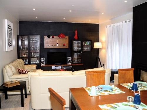 a living room with a white couch and a tv at Cabo da Vila Guesthouse in Ribeira Grande