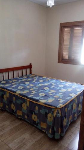 a bedroom with a bed with a blue and yellow blanket at Casa - Marcelo da Silva Américo in Imbé