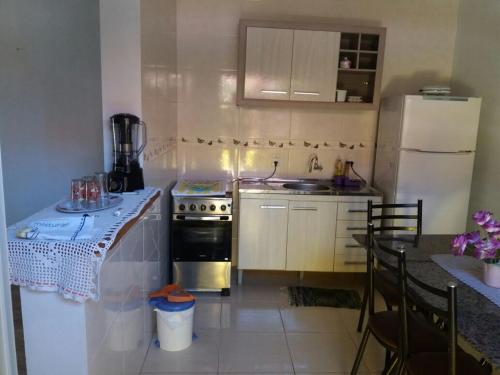 a kitchen with a stove and a table and a refrigerator at Casa - Jose Valdemar Americo in Imbé