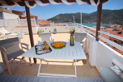 a table on a balcony with a bowl of fruit at Kamara House in Skopelos Town
