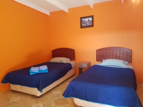 2 camas en una habitación con paredes de color naranja en Hostal Casa Colque, en San Pedro de Atacama