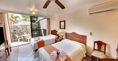 a hotel room with two beds and a balcony at Hotel Vista Hermosa in Cuernavaca