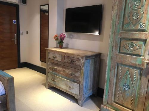 a bedroom with a dresser with a television on a wall at Charter House in Newport