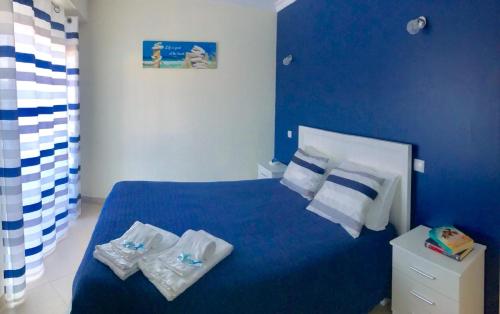Un dormitorio azul con una cama con toallas. en Central apartment-terrace and pool, en Cabanas de Tavira