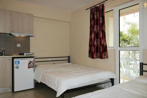 1 dormitorio con 1 cama, nevera y ventana en Mango, en Paralia Katerinis