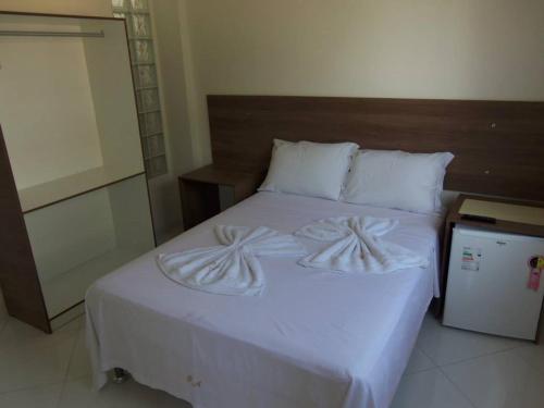 a white bed with white sheets and pillows on it at Pousada Águia in Vera Cruz de Itaparica