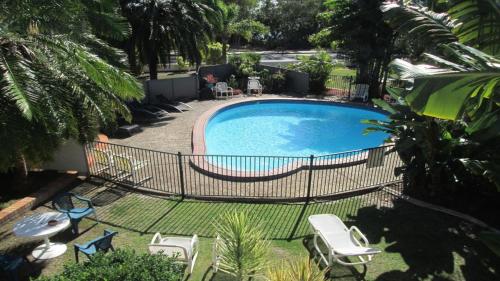 a swimming pool with a bunch of chairs around it at Tower Court Motel - adults only haven in Hervey Bay