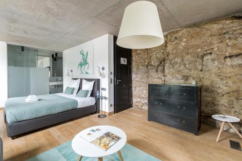 a bedroom with a bed and a stone wall at La Pipistrelle Hotel in Luxembourg