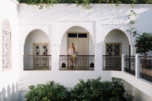 une femme debout sur un balcon dans un bâtiment blanc dans l'établissement Riad Clémentine, à Marrakech
