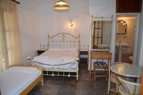 a bedroom with two beds and a table and a mirror at Hotel Rigakis in Pefkochori