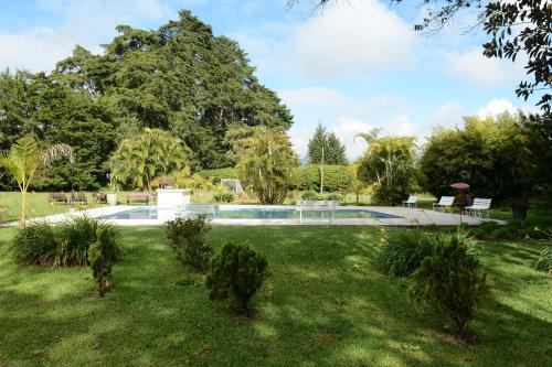 里奧內格羅的住宿－Casa Finca Corales Llano Grande 1，一个带游泳池和树木的花园