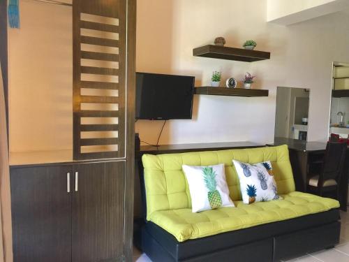 een gele bank in een woonkamer met een televisie bij Studio Unit Cityland Prime Residence in Tagaytay