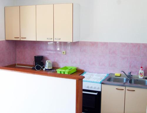 a kitchen with pink tiled walls and white cabinets at Apartment in Lopar/Insel Rab 17747 in Lopar