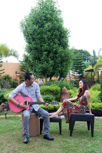 a man playing a guitar next to a woman at A&A Garden Suites in Tagaytay