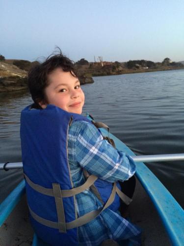 a young boy in a life vest on a boat on the water at Casona Patrimonial Cobquecura Hotel Boutique in Cobquecura