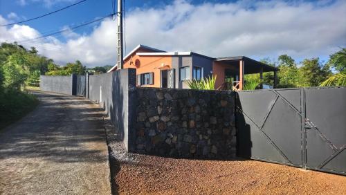 a fence with a stone wall next to a house at Les Bambous in Petite Île