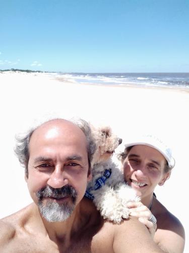 a man and a woman holding a dog on the beach at Playa, bosque y lago in Montevideo