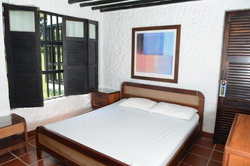 Un dormitorio con una cama con sábanas blancas y ventanas. en Casa Finca Corales Llano Grande 2, en Rionegro