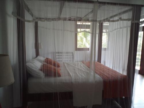 a bedroom with a canopy bed with red pillows at Beach Front Villa Nilaveli in Nilaveli