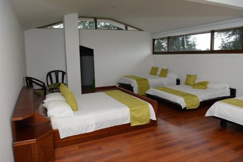 a bedroom with two beds and two windows at Casa Finca El Embrujo in Rionegro