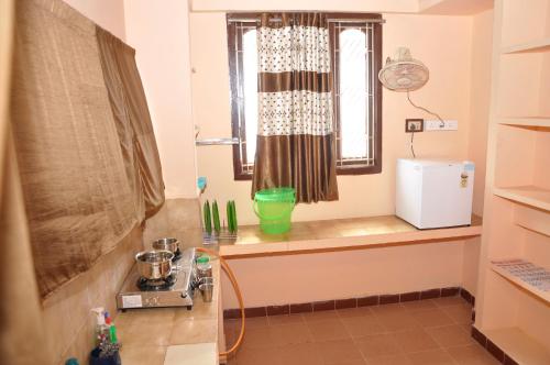 a kitchen with a counter with a window and a sink at Homestay Senthil Akam in Chidambaram