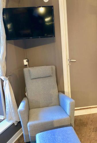 a blue chair sitting in a room with a tv at Brunsbo G:a Biskopsgård Hotell & Konferens in Skara