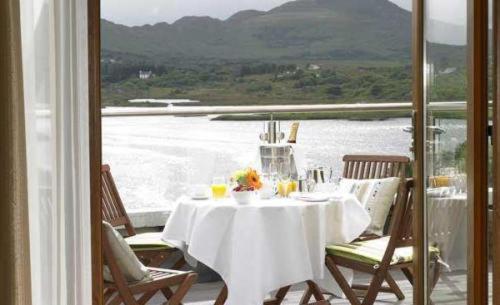 a table on a balcony with a view of the water at Sneem Hotel in Sneem