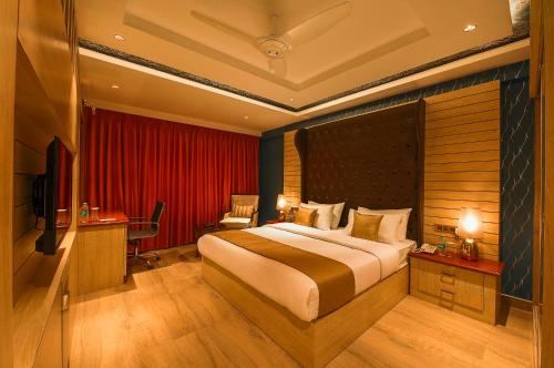 a bedroom with a large bed and a red curtain at White Lotus Hotel in Udupi