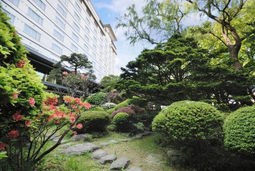a garden with bushes and flowers in front of a building at Takuboku Tei in Hakodate