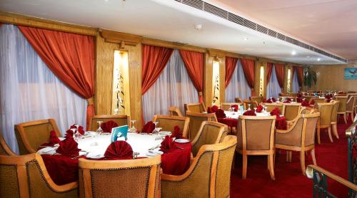 盧克索的住宿－Nile Carnival Cruise 4nt Lxr Thursday 3nt Asw Monday，一间设有桌椅和红色弓的用餐室