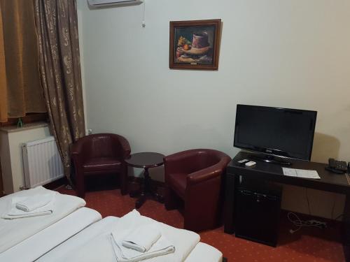 a hotel room with two beds and a desk with a television at Extra Jezero rooms in Palić